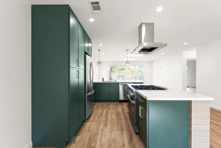 Tall green pantry cabinets beside the island and a 36-inch range