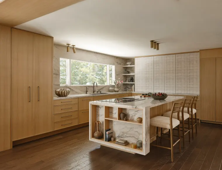 Floor-to-ceiling white oak cabinetry and a veined-stone island with open display shelving at its end