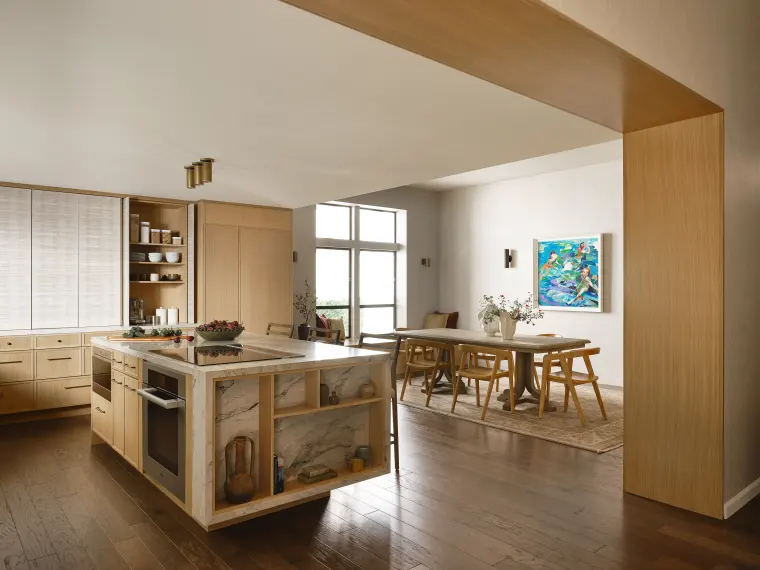 White oak kitchen opening through a wide wood-framed passage to the dining room