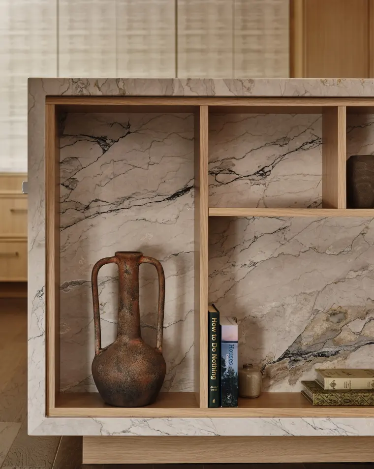 End of the island: open white oak shelving set into veined stone, with pottery and books