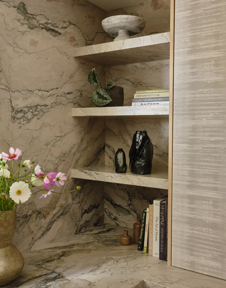Built-in stone niche with floating shelves, flowers, and ceramics
